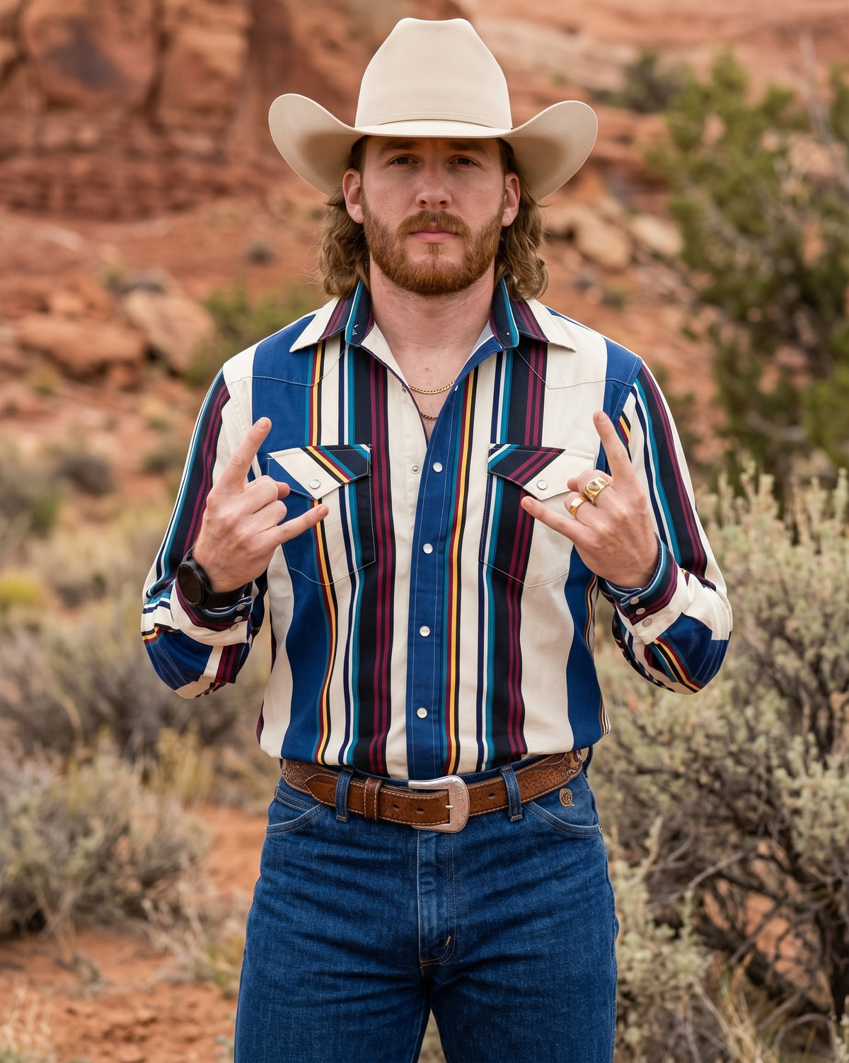 Front view of cowboy wearing Pecos Western blue and cream multi-striped pearl snap shirt in desert canyon landscape