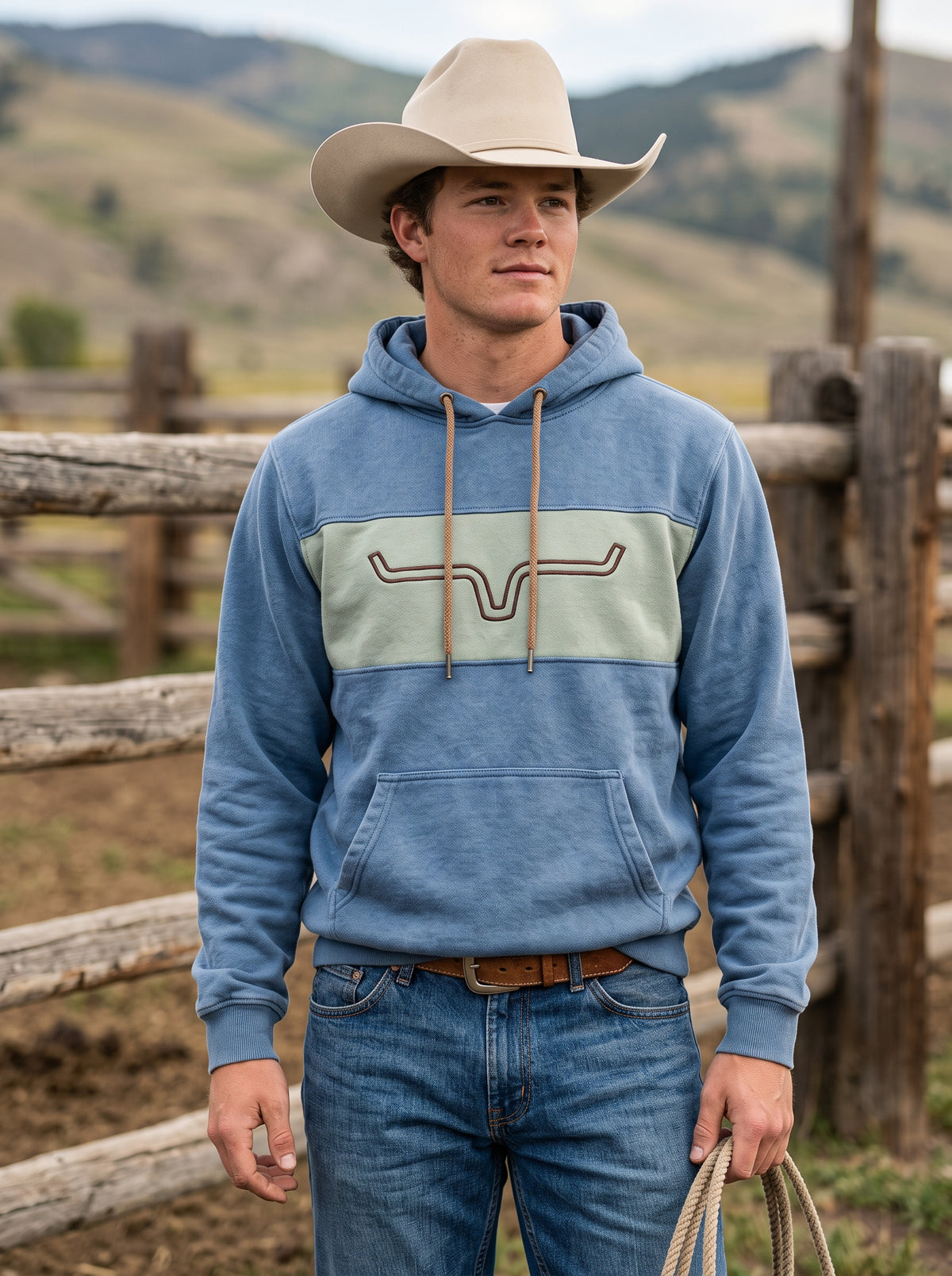 Front view of man in dusty blue Western hoodie with sage green longhorn chest stripe and cowboy hat