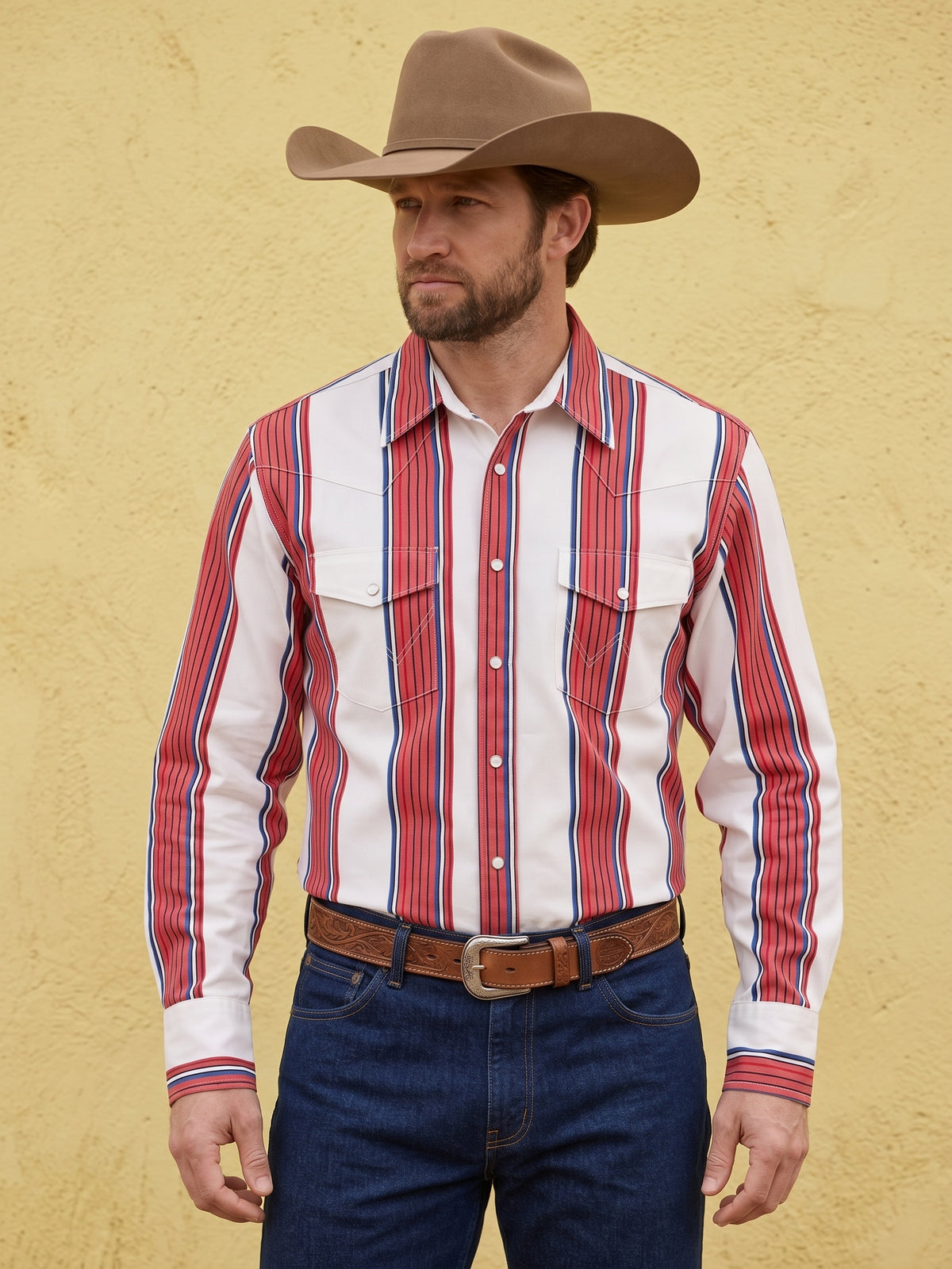 Front view of cowboy wearing Pecos Western white, red, and blue striped pearl snap shirt against a stucco wall