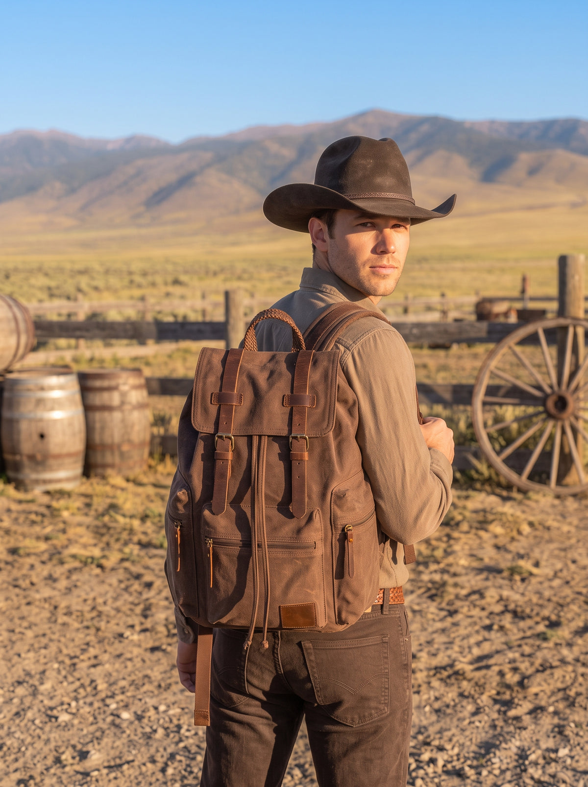 Men's coffee brown canvas rucksack worn outdoors in an open Western ranch setting